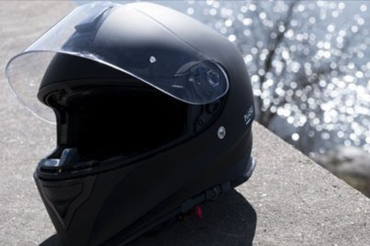 Integralhjälm som ligger på en mur. Och vatten som glittrar en bit nedanför.